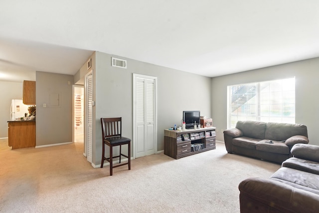 living area with visible vents, baseboards, and light carpet