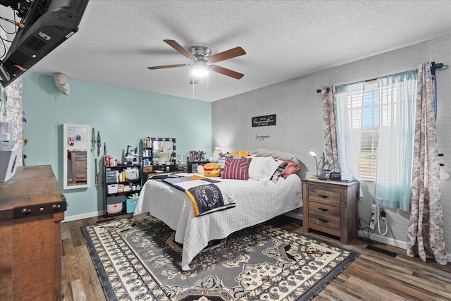 bedroom featuring a ceiling fan, wood finished floors, baseboards, and a textured ceiling