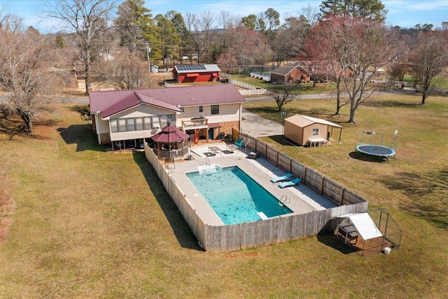 view of pool with a lawn, a fenced backyard, an outdoor structure, a fenced in pool, and a patio area