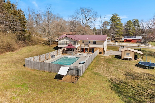 back of property with fence, a fenced in pool, and a lawn