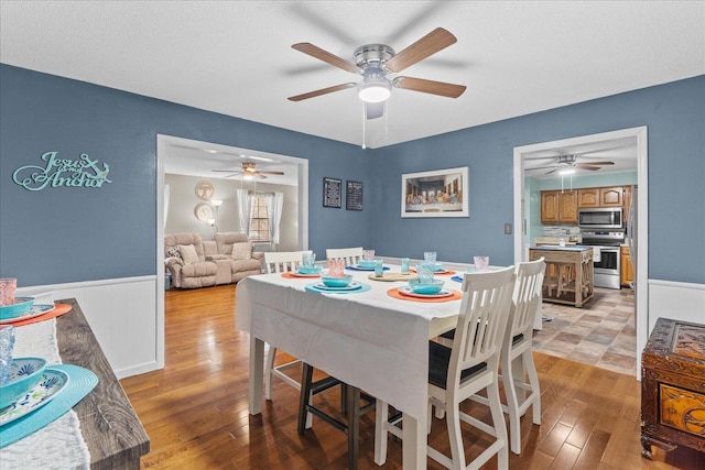 dining space with light wood-style flooring and a wainscoted wall