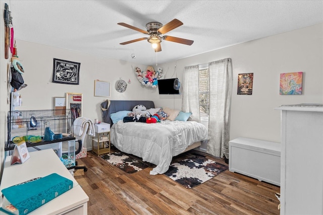 bedroom with ceiling fan, a textured ceiling, and wood finished floors