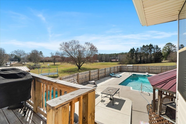 view of pool featuring a fenced in pool, a trampoline, a lawn, a fenced backyard, and a patio area