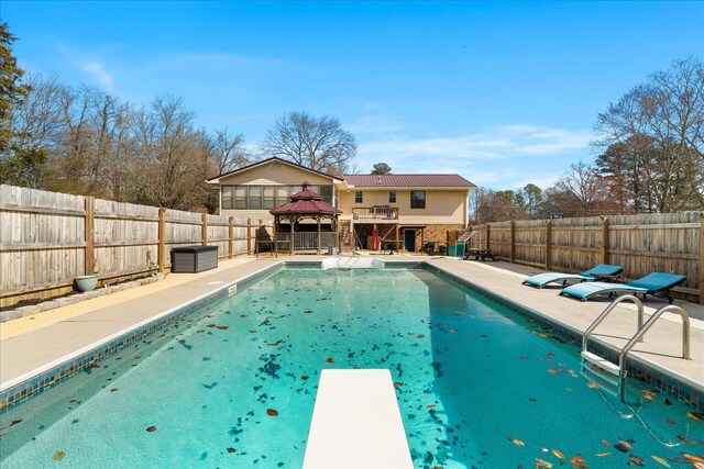 view of swimming pool with a gazebo, a fenced in pool, a fenced backyard, and a diving board