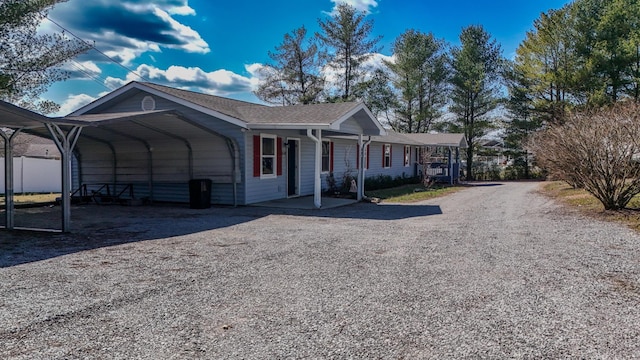 view of front facade with a carport, covered porch, and gravel driveway