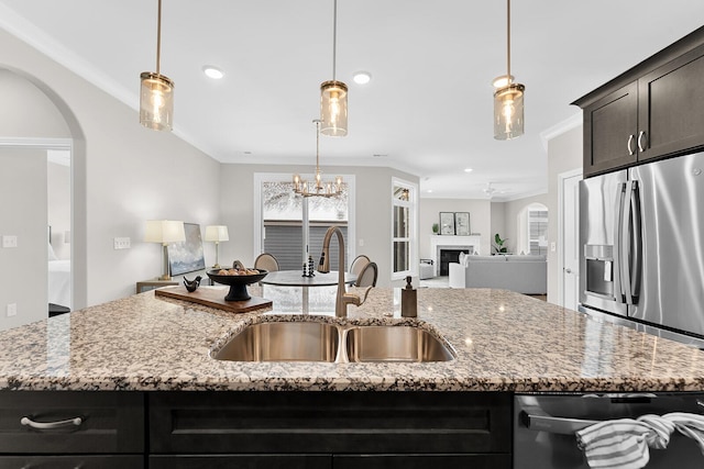 kitchen with an island with sink, ornamental molding, a sink, appliances with stainless steel finishes, and open floor plan