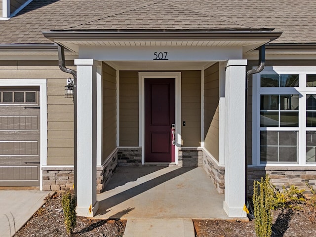 doorway to property with stone siding and roof with shingles