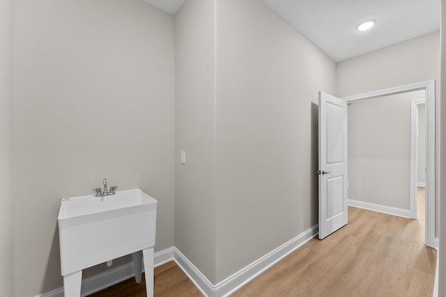 interior space featuring a sink, baseboards, and light wood-style flooring