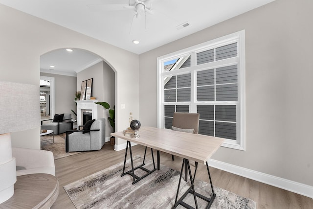 office featuring visible vents, arched walkways, baseboards, and wood finished floors
