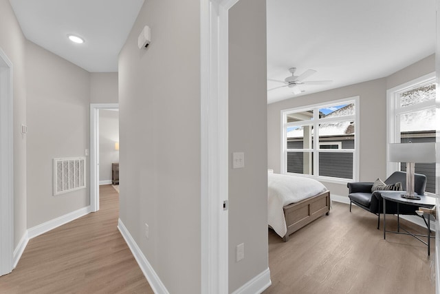 bedroom with a ceiling fan, light wood-style flooring, baseboards, and visible vents