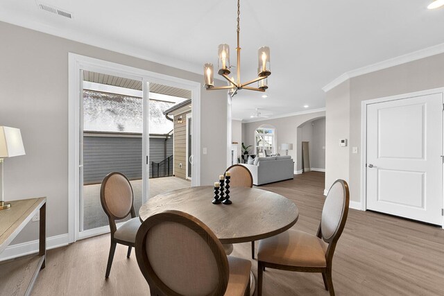 dining room with baseboards, visible vents, crown molding, ceiling fan with notable chandelier, and light wood-type flooring