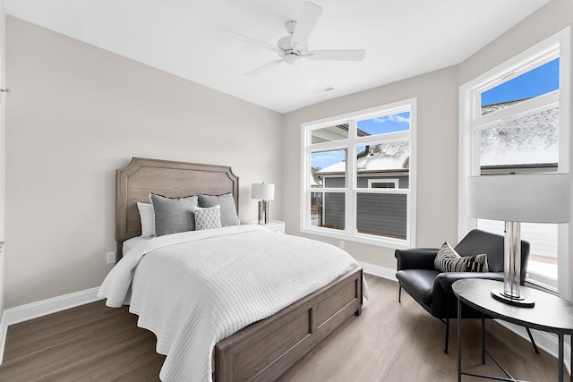 bedroom with ceiling fan, visible vents, baseboards, and wood finished floors