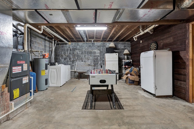 basement featuring wood walls, white refrigerator, washing machine and dryer, and water heater