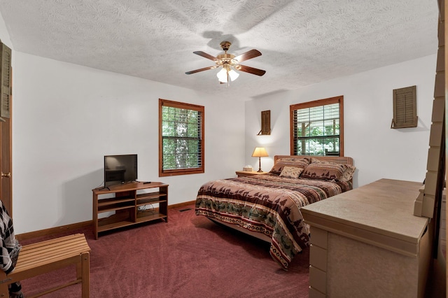 bedroom featuring dark colored carpet, ceiling fan, a textured ceiling, and multiple windows