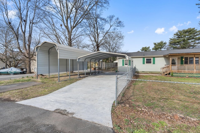 view of front of house featuring a carport, concrete driveway, a front lawn, and fence