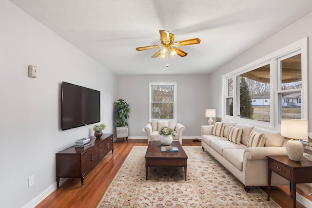 living room featuring baseboards, light wood-style floors, and a ceiling fan