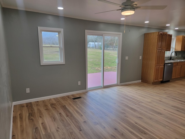 unfurnished living room featuring ornamental molding, sink, ceiling fan, and light wood-type flooring