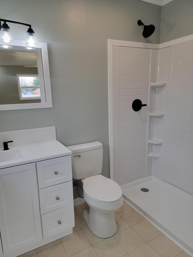 bathroom featuring vanity, toilet, tile patterned flooring, and a tile shower