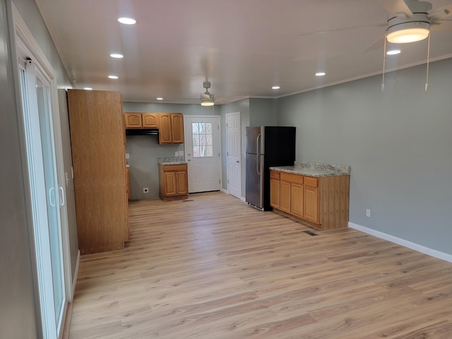 kitchen featuring crown molding, stainless steel fridge, ceiling fan, light stone countertops, and light hardwood / wood-style floors