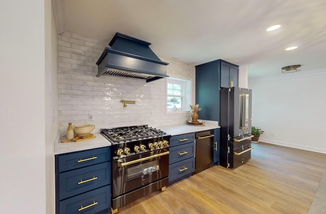 kitchen featuring high end appliances, light hardwood / wood-style floors, blue cabinetry, decorative backsplash, and custom range hood