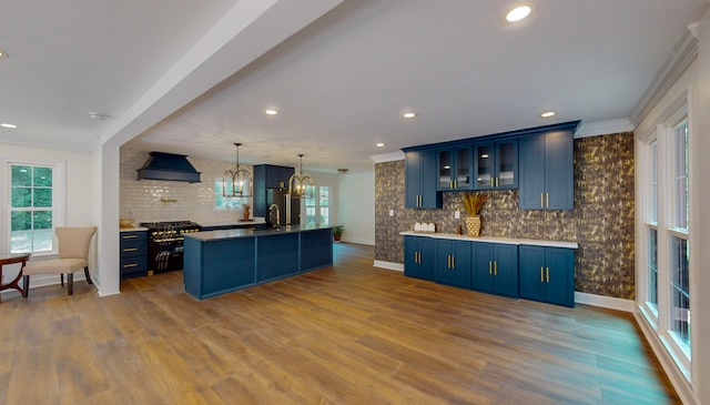 kitchen featuring decorative backsplash, blue cabinetry, sink, and custom exhaust hood