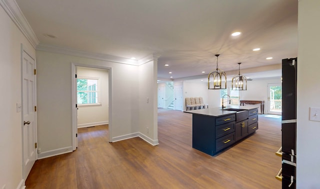 kitchen with sink, pendant lighting, plenty of natural light, and an island with sink