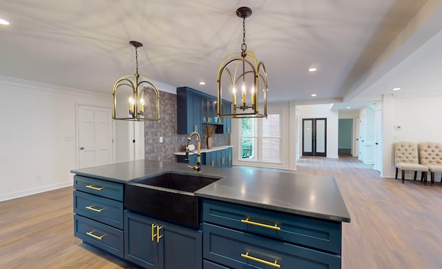 kitchen with decorative backsplash, blue cabinets, sink, and an inviting chandelier