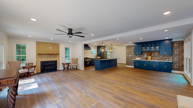 living room with ceiling fan, a fireplace, ornamental molding, and hardwood / wood-style floors