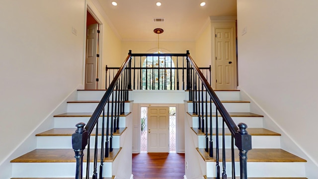 stairway featuring an inviting chandelier and wood-type flooring