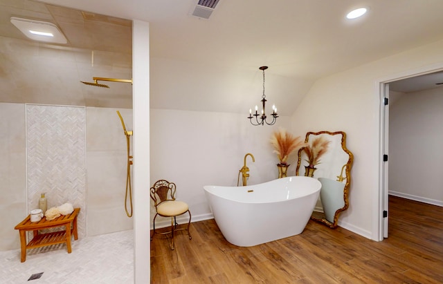 bathroom with vaulted ceiling, an inviting chandelier, a tub to relax in, and wood-type flooring