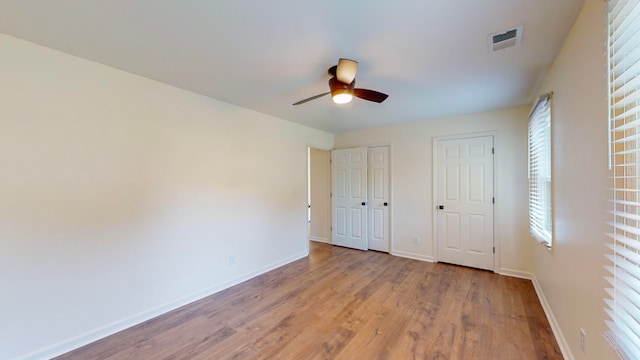 unfurnished bedroom with ceiling fan, two closets, and light hardwood / wood-style flooring