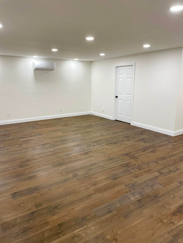 basement featuring dark hardwood / wood-style flooring and a wall unit AC