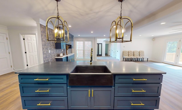 kitchen with light hardwood / wood-style floors, sink, crown molding, hanging light fixtures, and blue cabinets