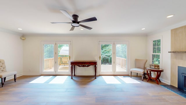 living area featuring crown molding, a healthy amount of sunlight, hardwood / wood-style flooring, and ceiling fan