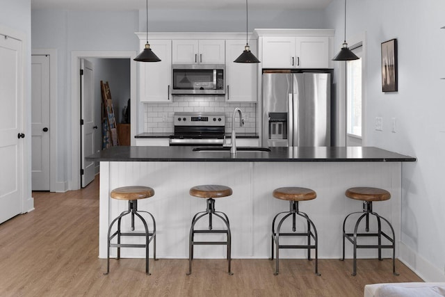 kitchen with appliances with stainless steel finishes, decorative light fixtures, and white cabinets