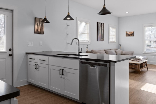 kitchen with dishwasher, dark countertops, a sink, and pendant lighting