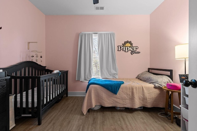 bedroom with wood finished floors, visible vents, and baseboards