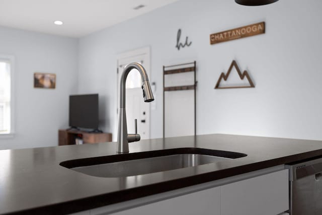 kitchen with dark countertops, a sink, stainless steel dishwasher, and recessed lighting