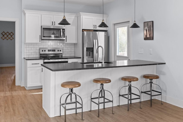 kitchen with stainless steel appliances, a breakfast bar area, dark countertops, and white cabinets