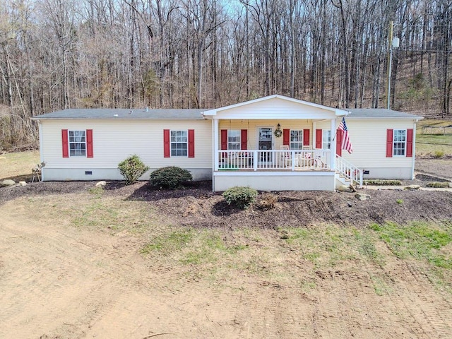 manufactured / mobile home featuring a porch, a view of trees, and crawl space