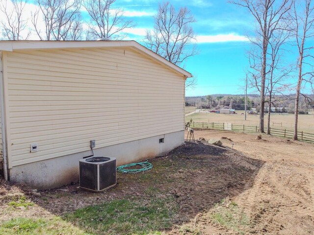 view of side of property featuring crawl space, central air condition unit, and fence