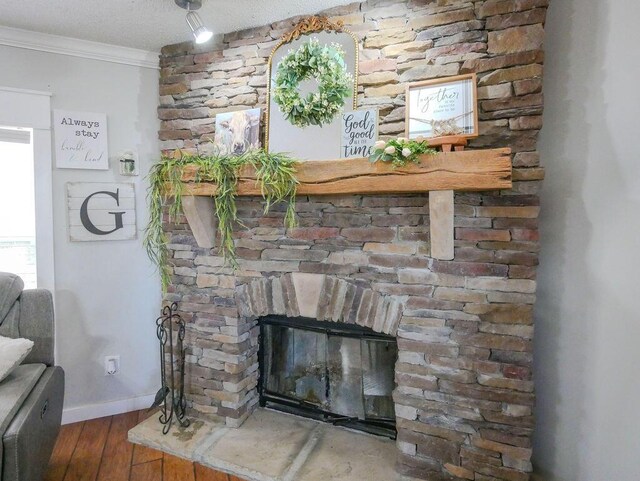 interior details featuring crown molding, baseboards, a fireplace, wood finished floors, and a textured ceiling