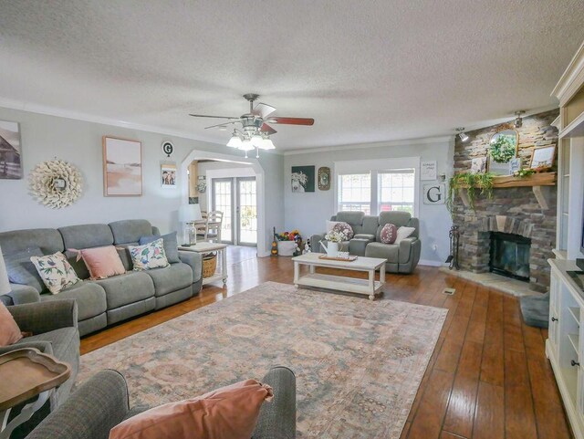 living room featuring hardwood / wood-style floors, a textured ceiling, a fireplace, and ornamental molding