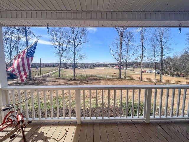 wooden terrace featuring a rural view and fence