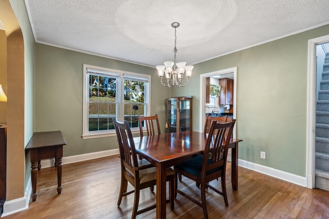 dining room featuring a notable chandelier, crown molding, dark hardwood / wood-style flooring, and a textured ceiling