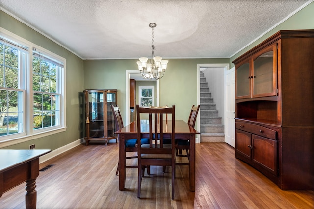 dining area featuring a chandelier, crown molding, dark wood-type flooring, and a textured ceiling