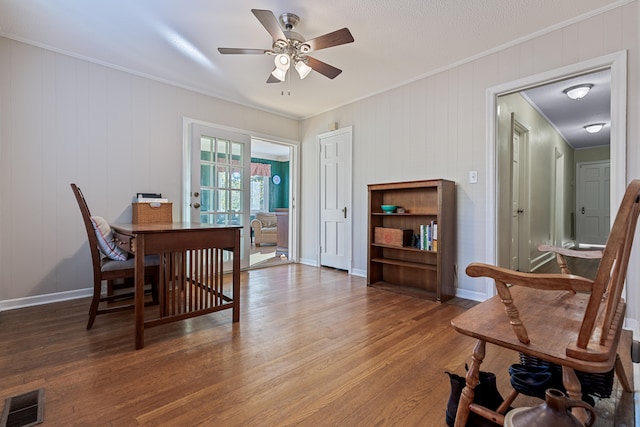 dining area with ceiling fan, wood walls, wood-type flooring, and ornamental molding