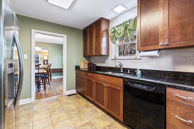 kitchen featuring stainless steel fridge with ice dispenser, dishwasher, dark stone counters, and sink