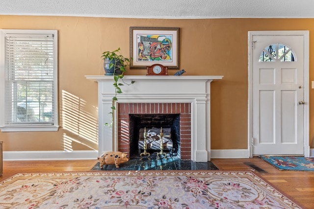 living room featuring hardwood / wood-style floors, a textured ceiling, and a brick fireplace