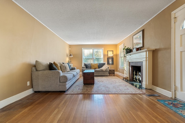 living room with hardwood / wood-style flooring, a textured ceiling, and a brick fireplace